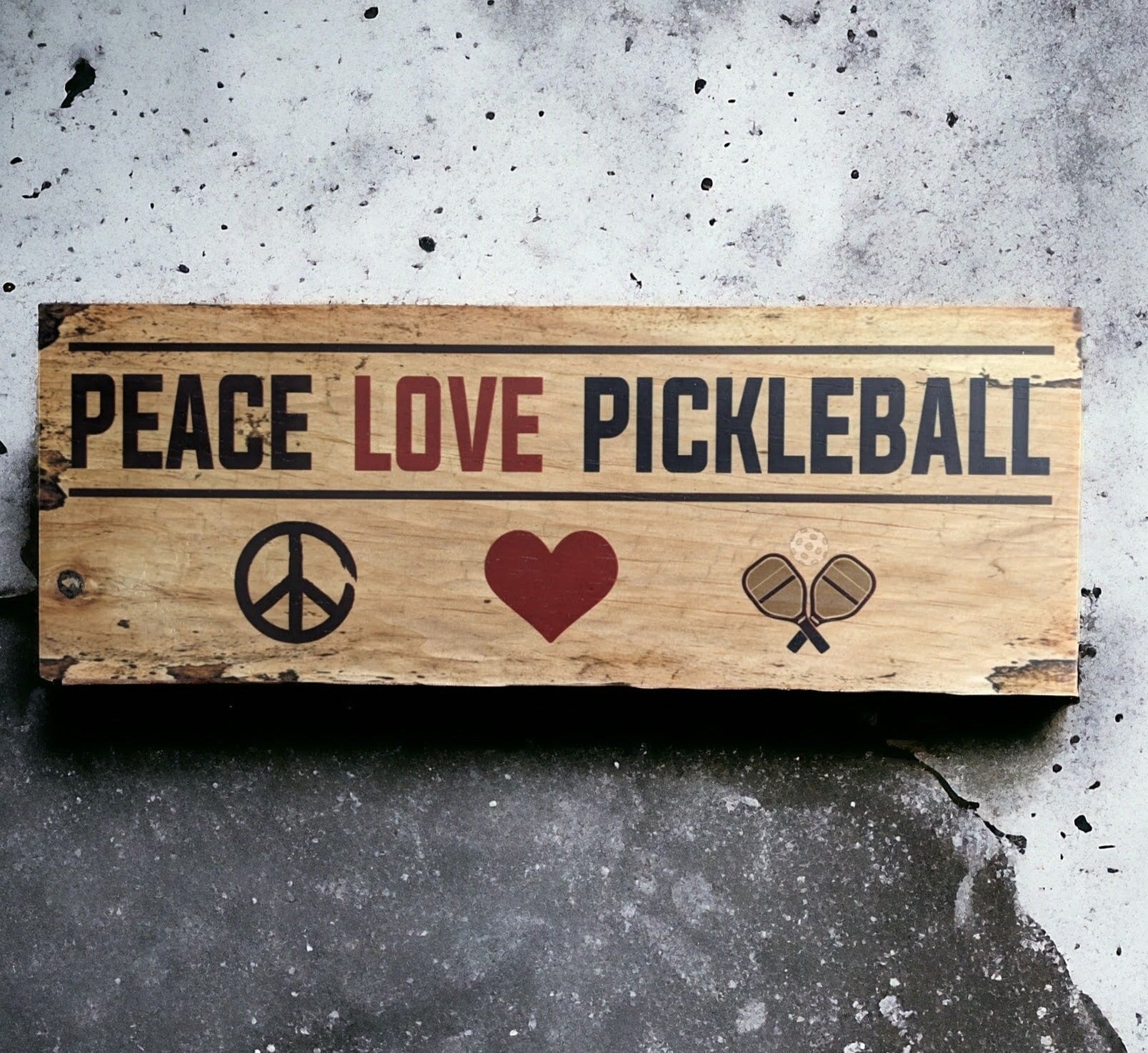 A Pickleball sign made of solid pine wood and features the inscription Peace Love Pickleball with a peace sign, heart and rackets and ball