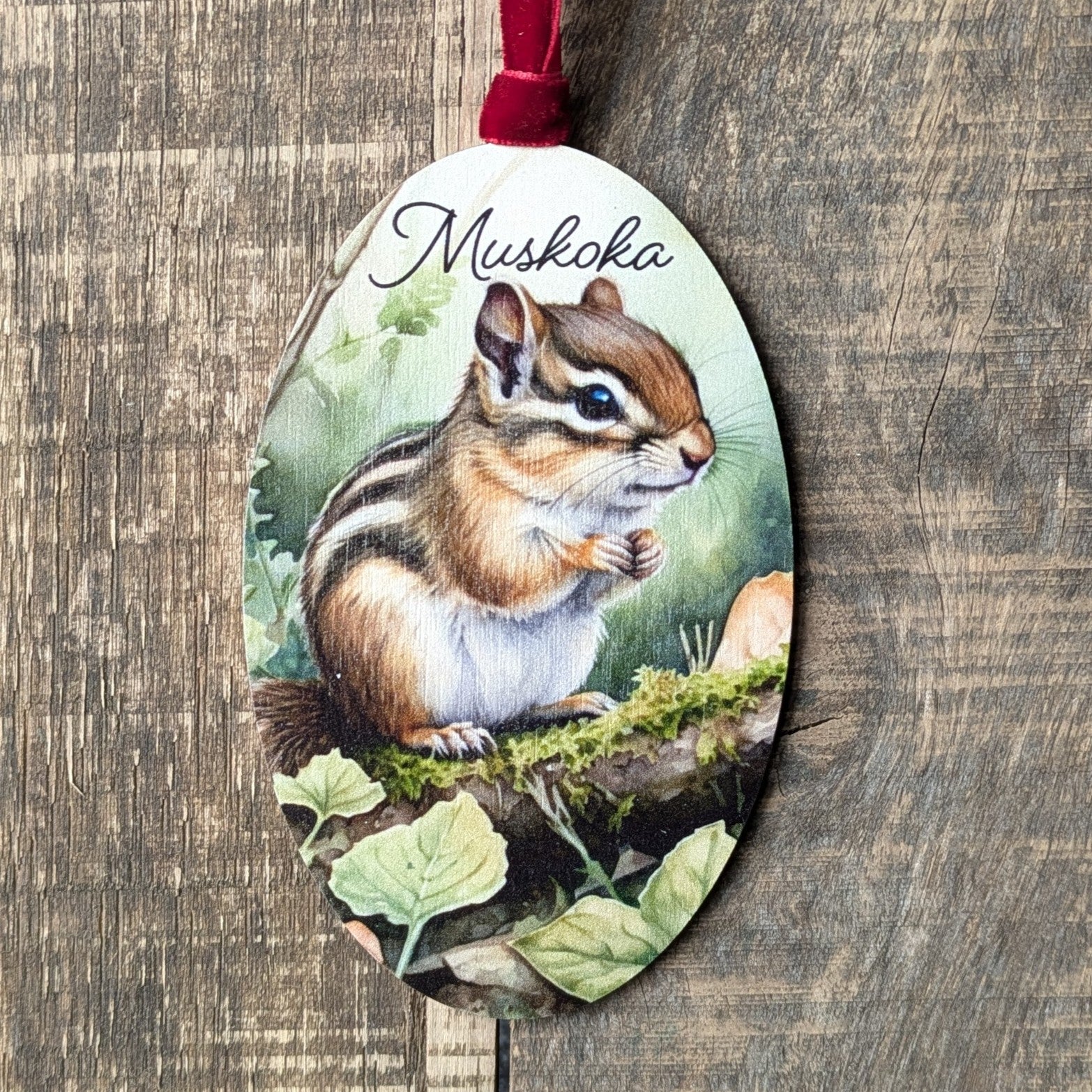 Decorative ornament with a chipmunk illustration and 'Muskoka' text on a wooden background
