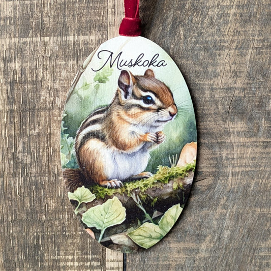 Decorative ornament with a chipmunk illustration and 'Muskoka' text on a wooden background