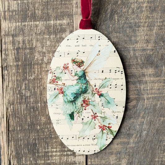 Decorative ornament with a fairy and holly design on a wooden surface