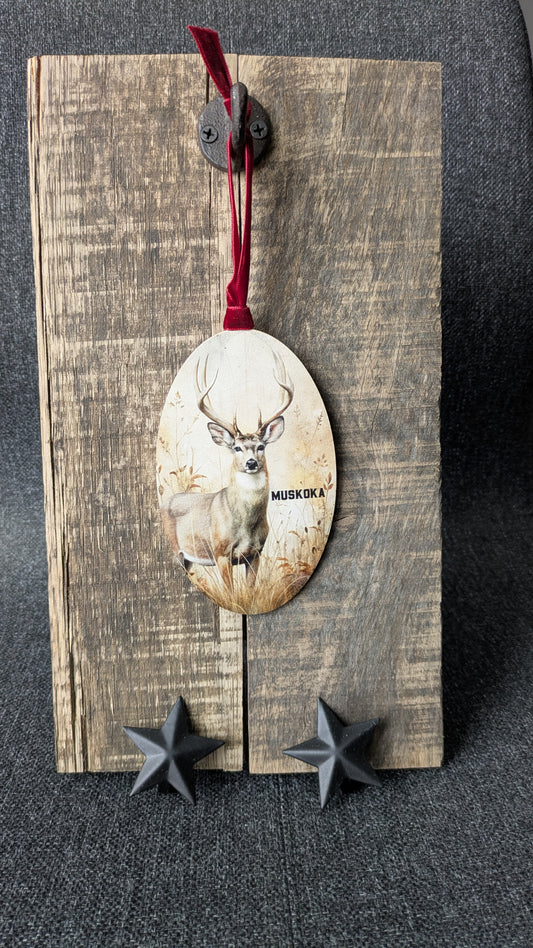 Decorative wooden ornament with a deer illustration and red ribbon on a dark surface