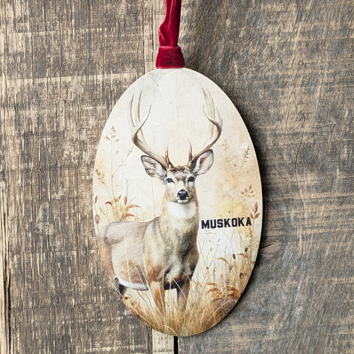 Decorative ornament with a deer design and 'Muskoka' text on a wooden background