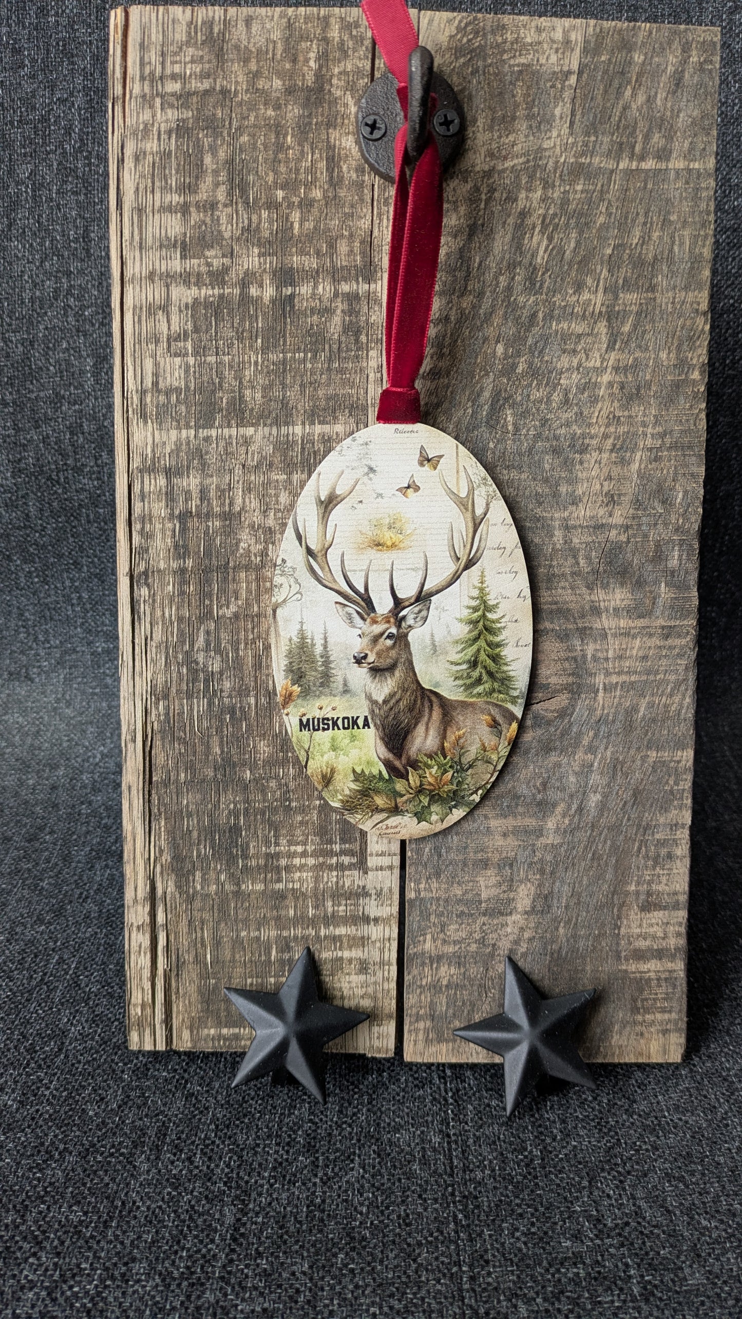 Decorative wooden ornament with deer design on a rustic wooden board.