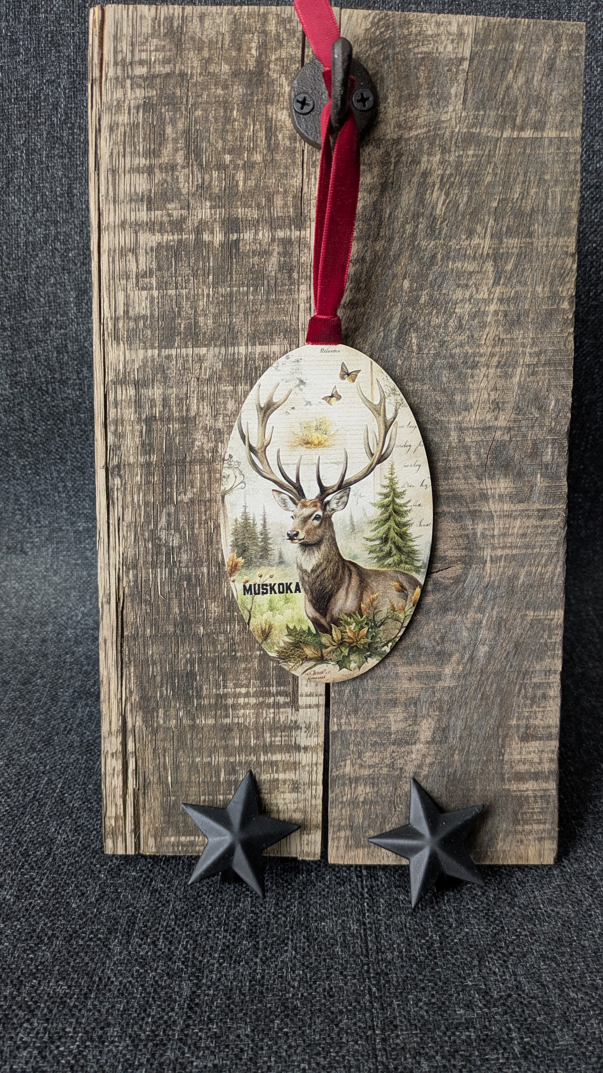 Decorative wooden ornament with deer design on a rustic wooden board.